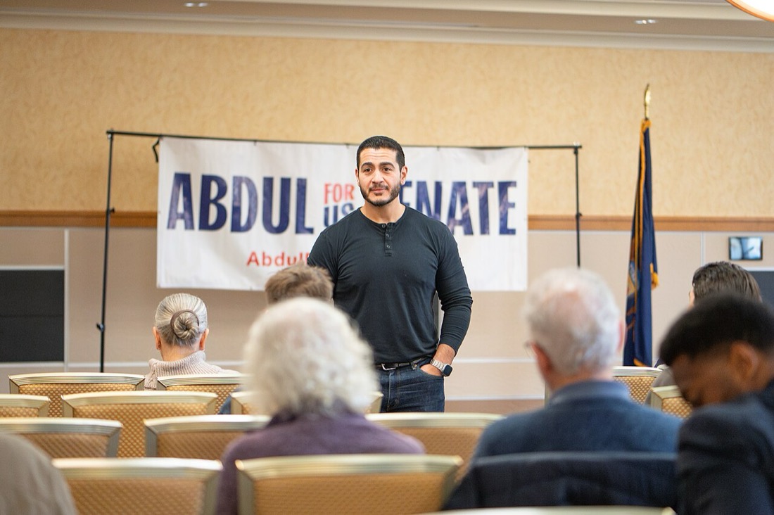 Abdul El-Sayed stands in front of an Abdul for US Senate banner, talking to voters at Michigan Technological University