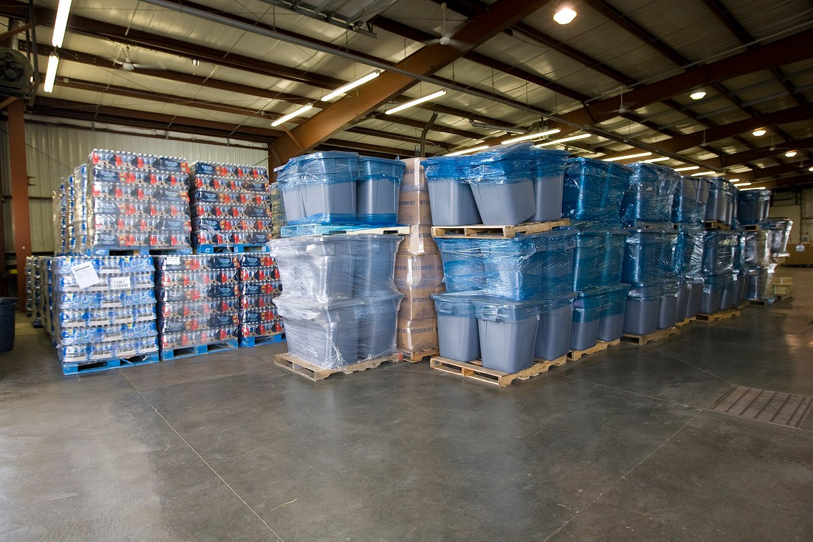 Pallets of bottled water and plastic tubs stacked inside a warehouse