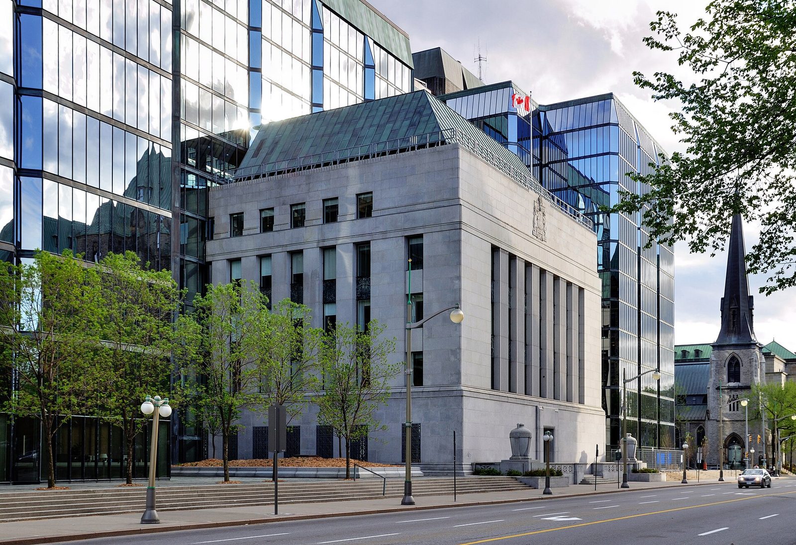 Stone central-bank building with glass office towers and street, Canada