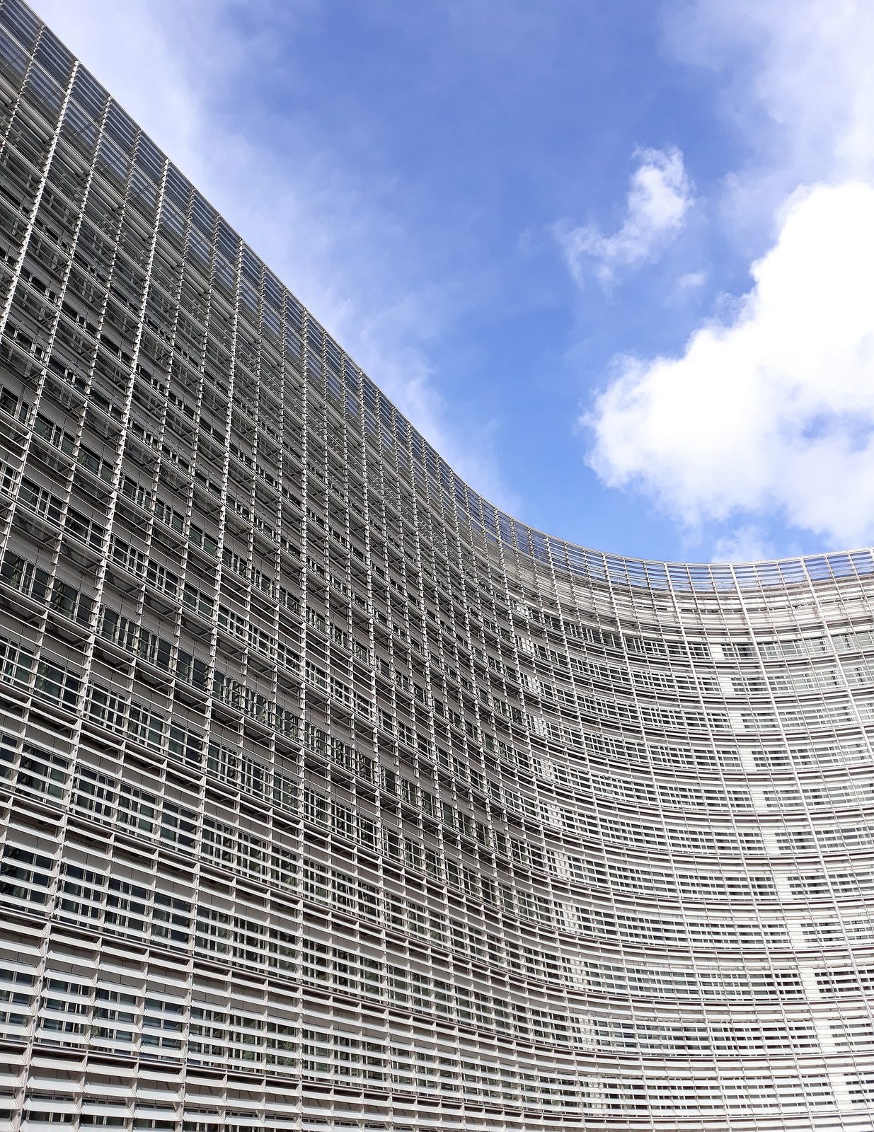 curved facade of Berlaymont building against blue sky, Brussels