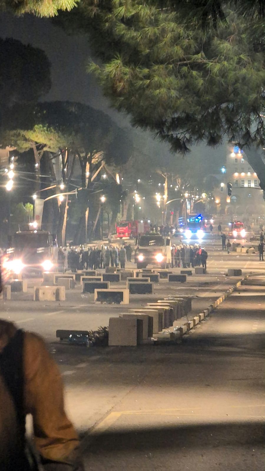 Wide night scene, police lines, water cannon and bright lights