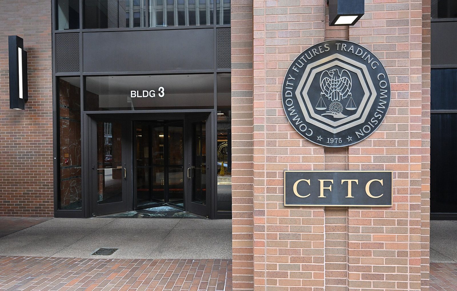 Bronze CFTC sign beside revolving entrance doors on brick facade