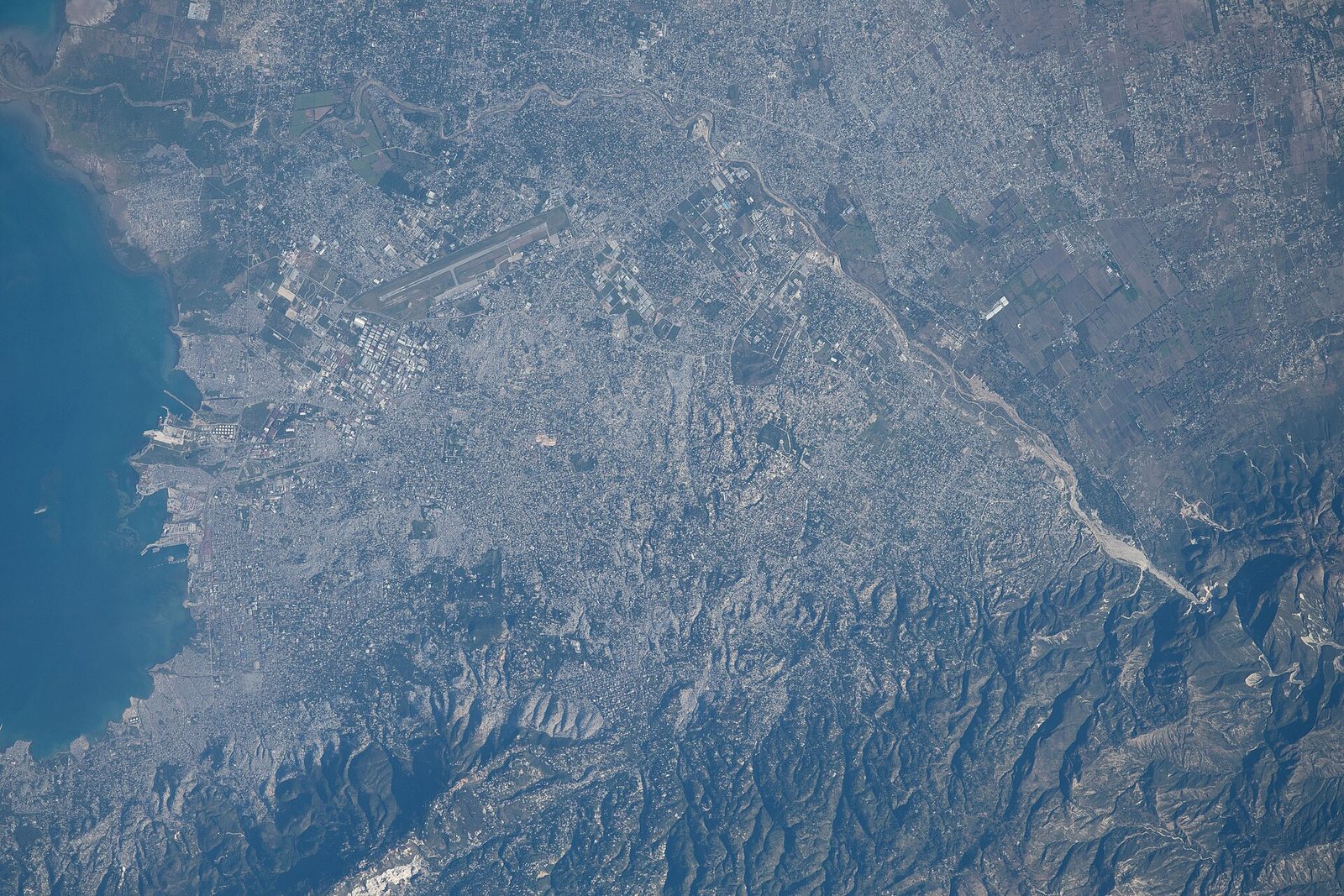 Wide satellite/aerial view of sprawling urban area, runway by the coast, Port-au-Prince