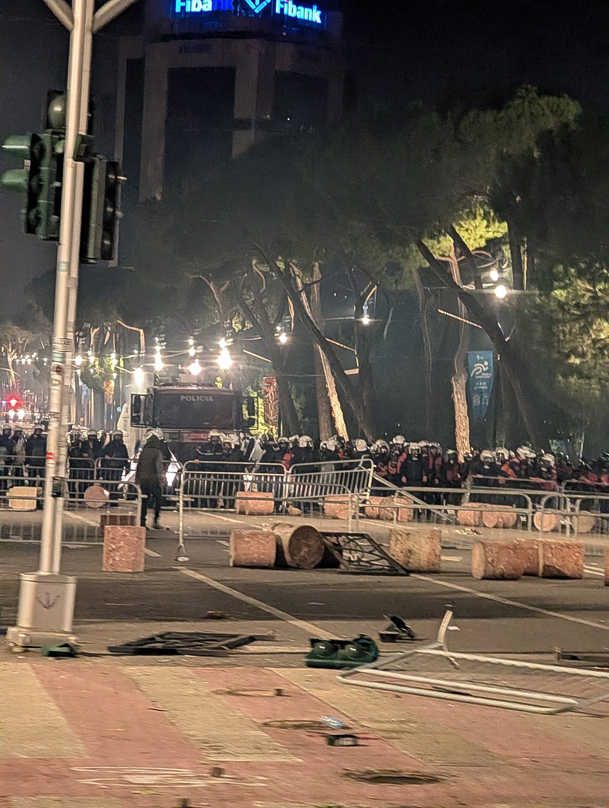 Riot police lined on boulevard, barricades and debris in foreground