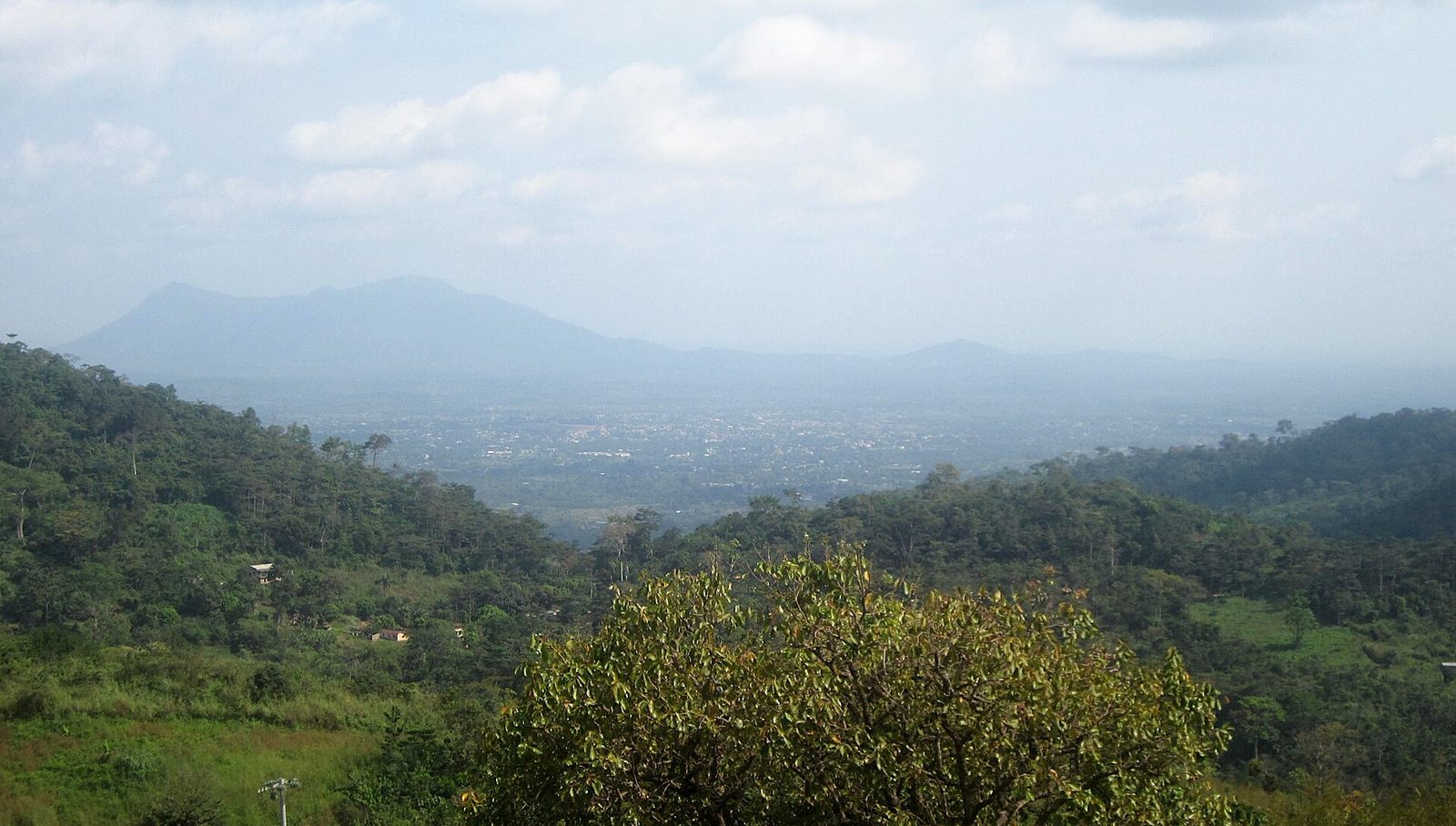 valley view with forested hills, faint settlement in the distance, Kpalimé