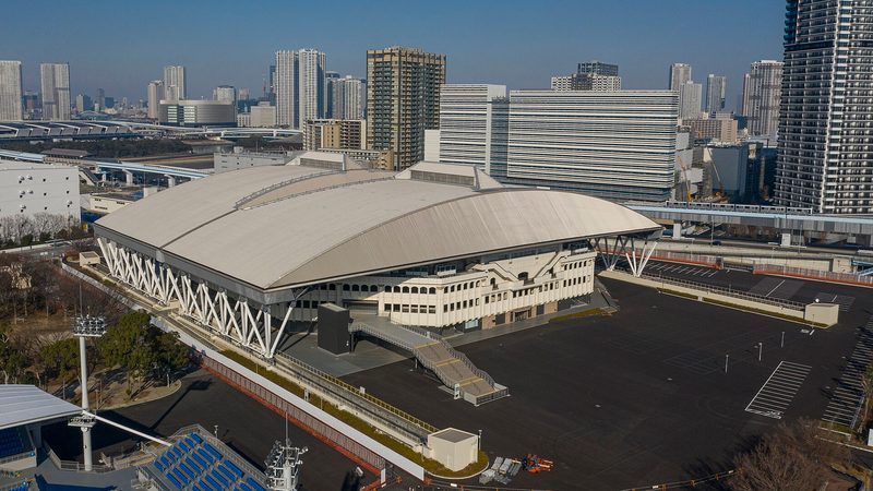 Aerial view of a large domed sports arena amid city buildings, Ariake Coliseum