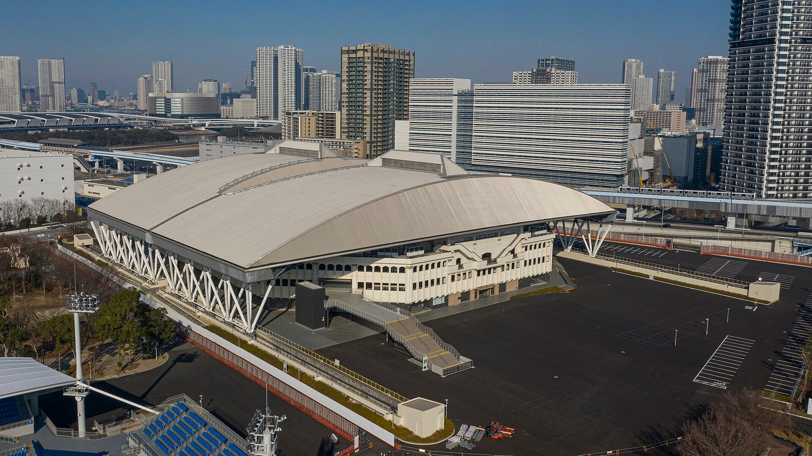 Aerial view of a large domed sports arena amid city buildings, Ariake Coliseum