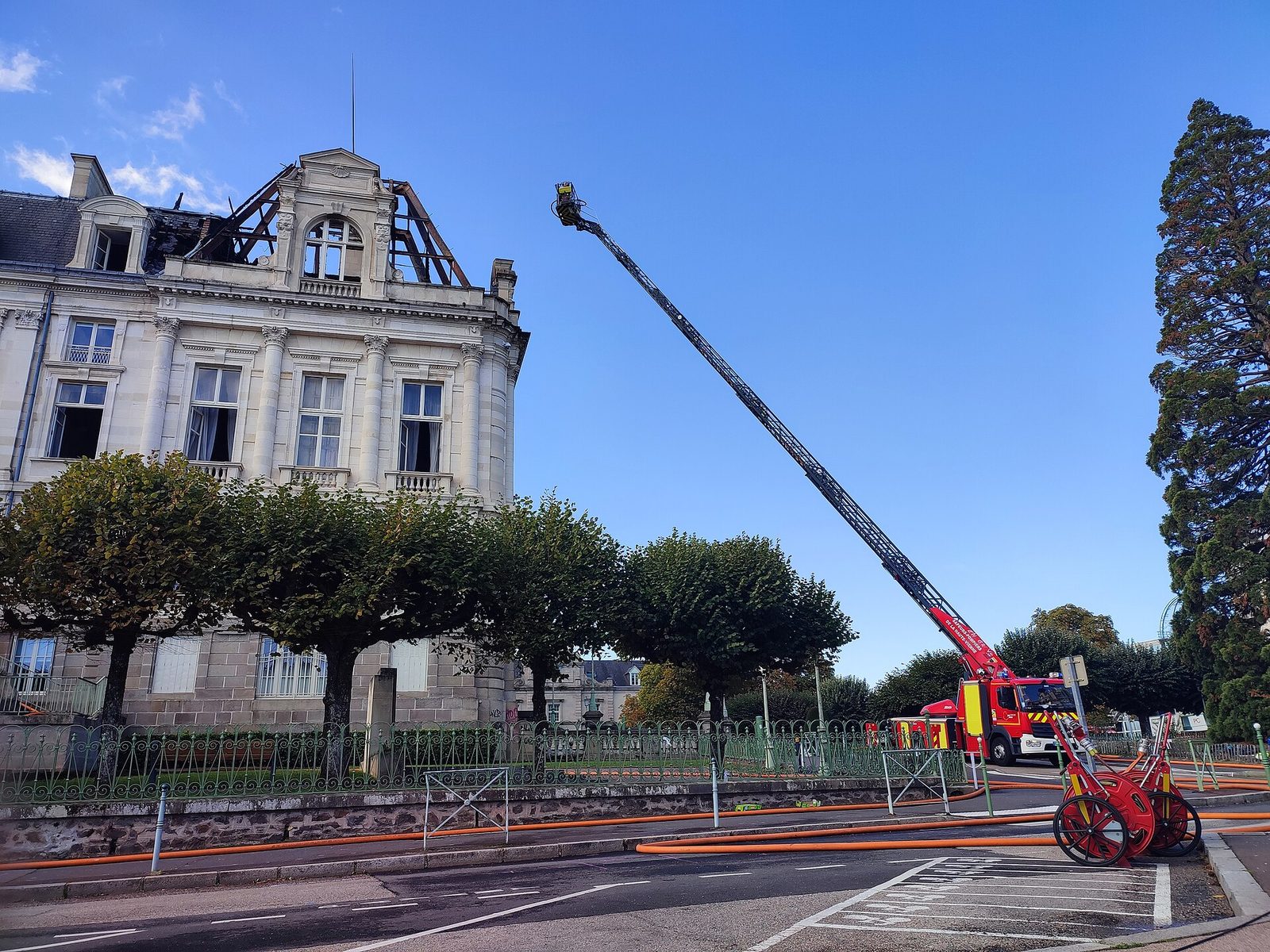 Burnt roof and raised fire ladder, fire engine on street