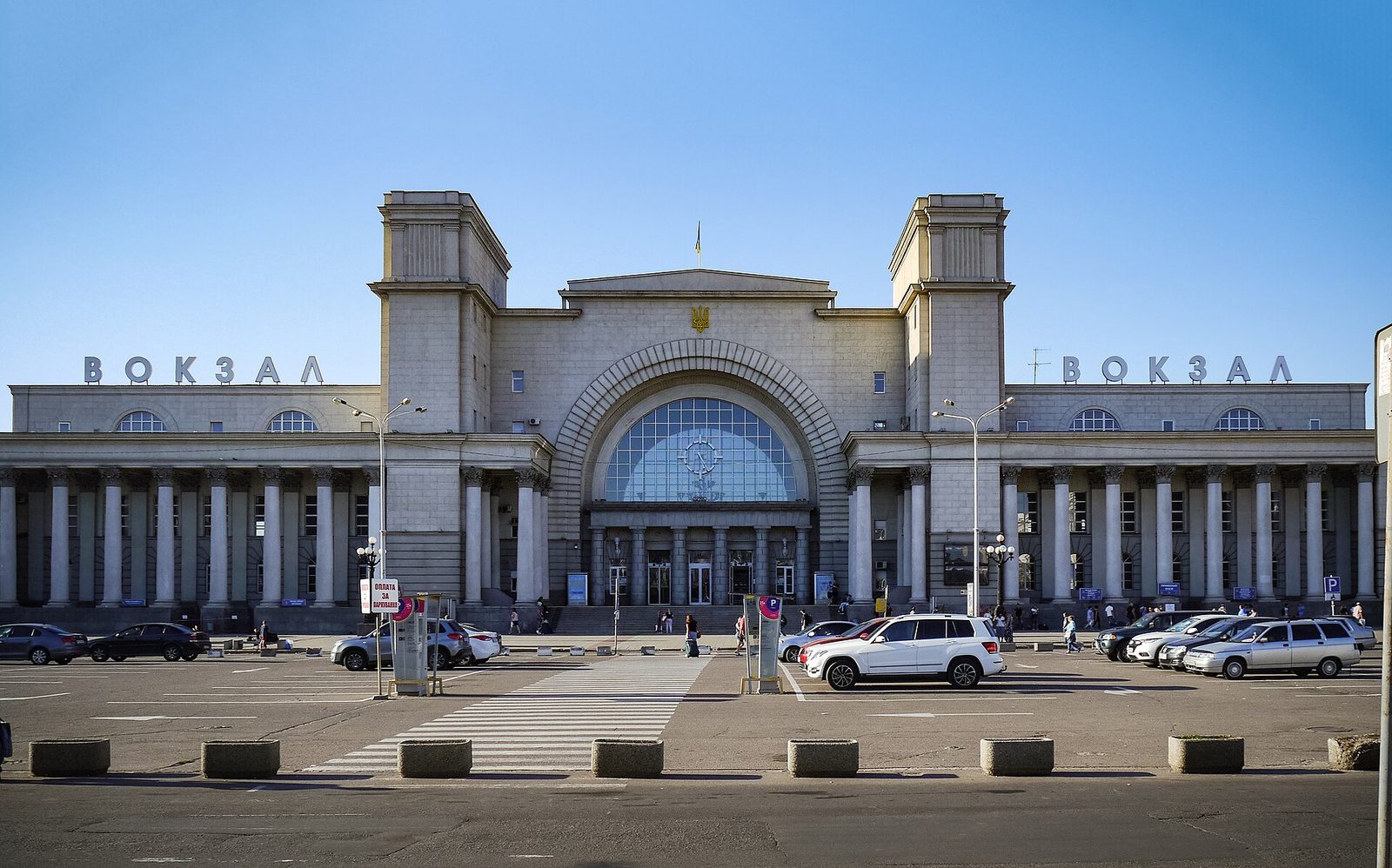 Front of large railway station building, parked cars, zebra crossing