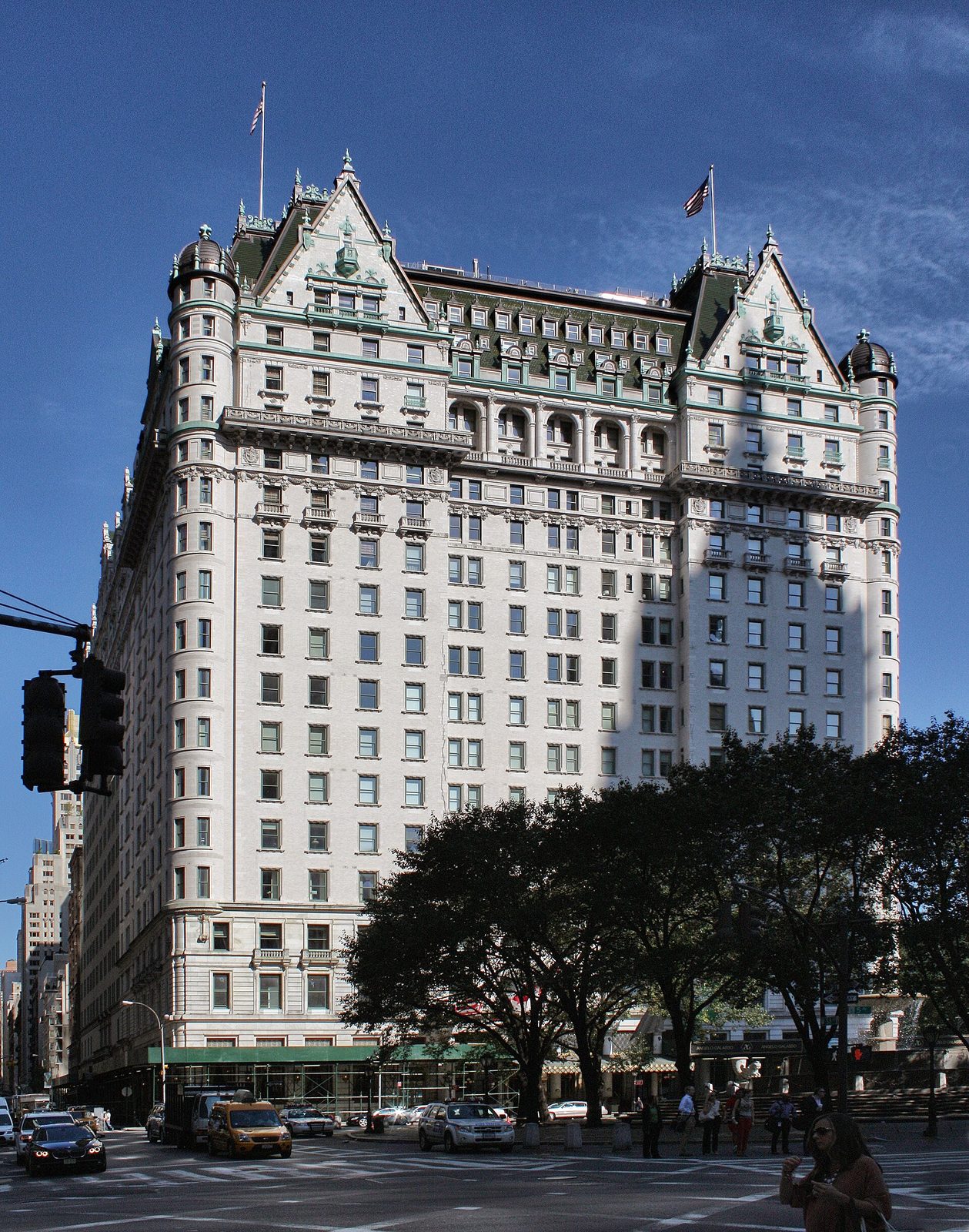 Large ornate white hotel building with green roof and flags, clear sky, Plaza Hotel