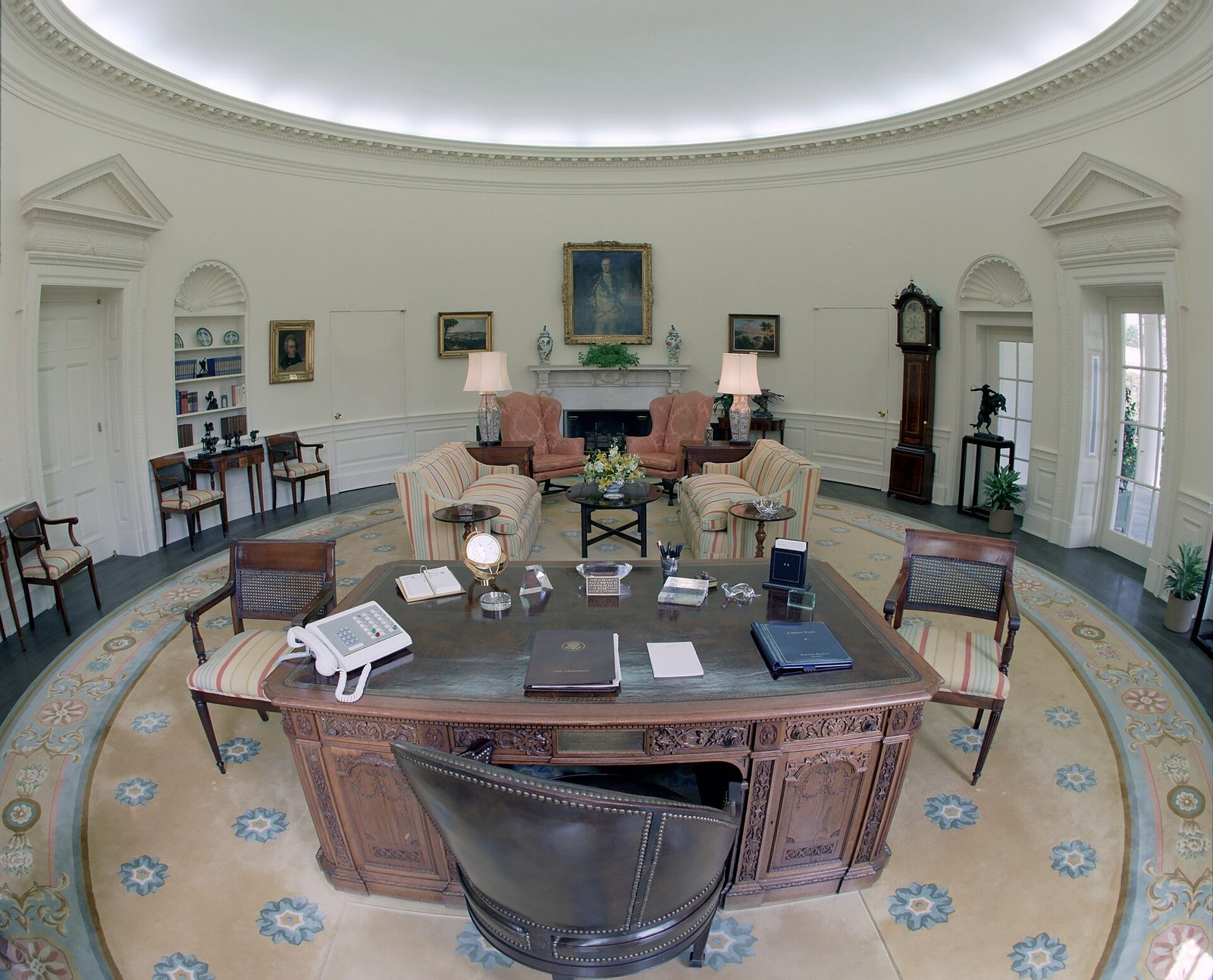 Empty formal oval-shaped office, carved desk and seating visible, White House