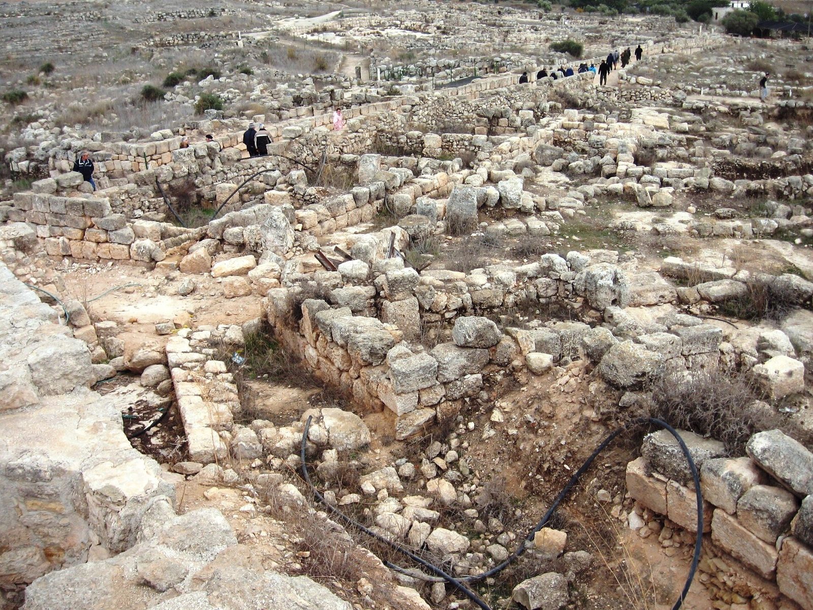 stone ruins of an archaeological site, people on paths, Susya