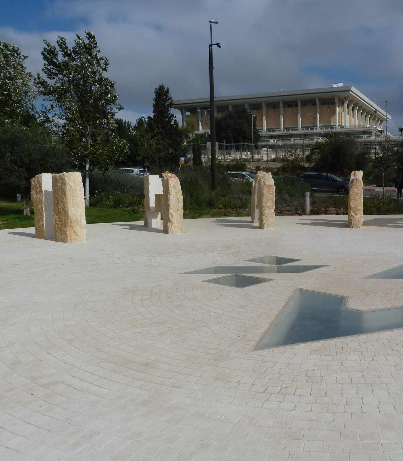 Stone sculptures in foreground, Knesset building visible in background