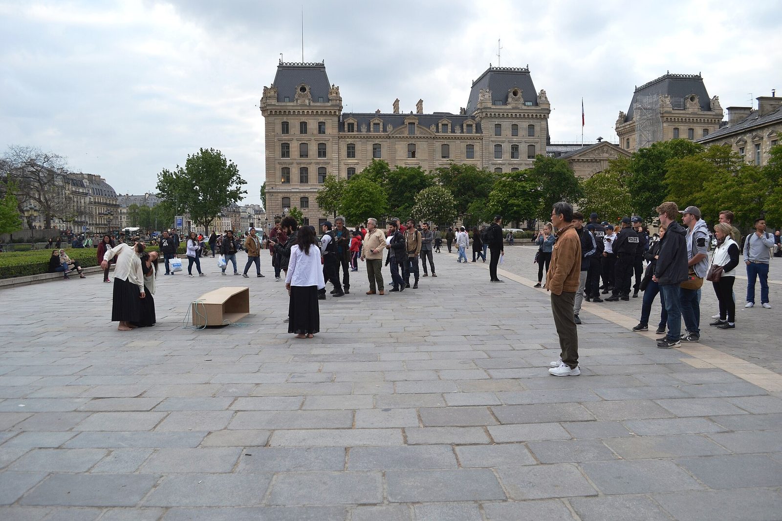 Wide public square near a large stone government building, small crowd, Paris