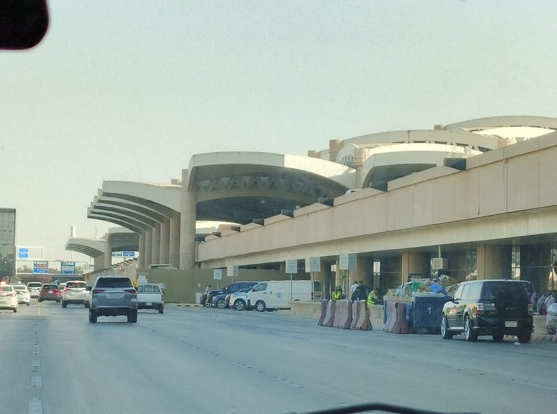 terminal building with curved canopies, cars on roadway, King Khalid International Airport