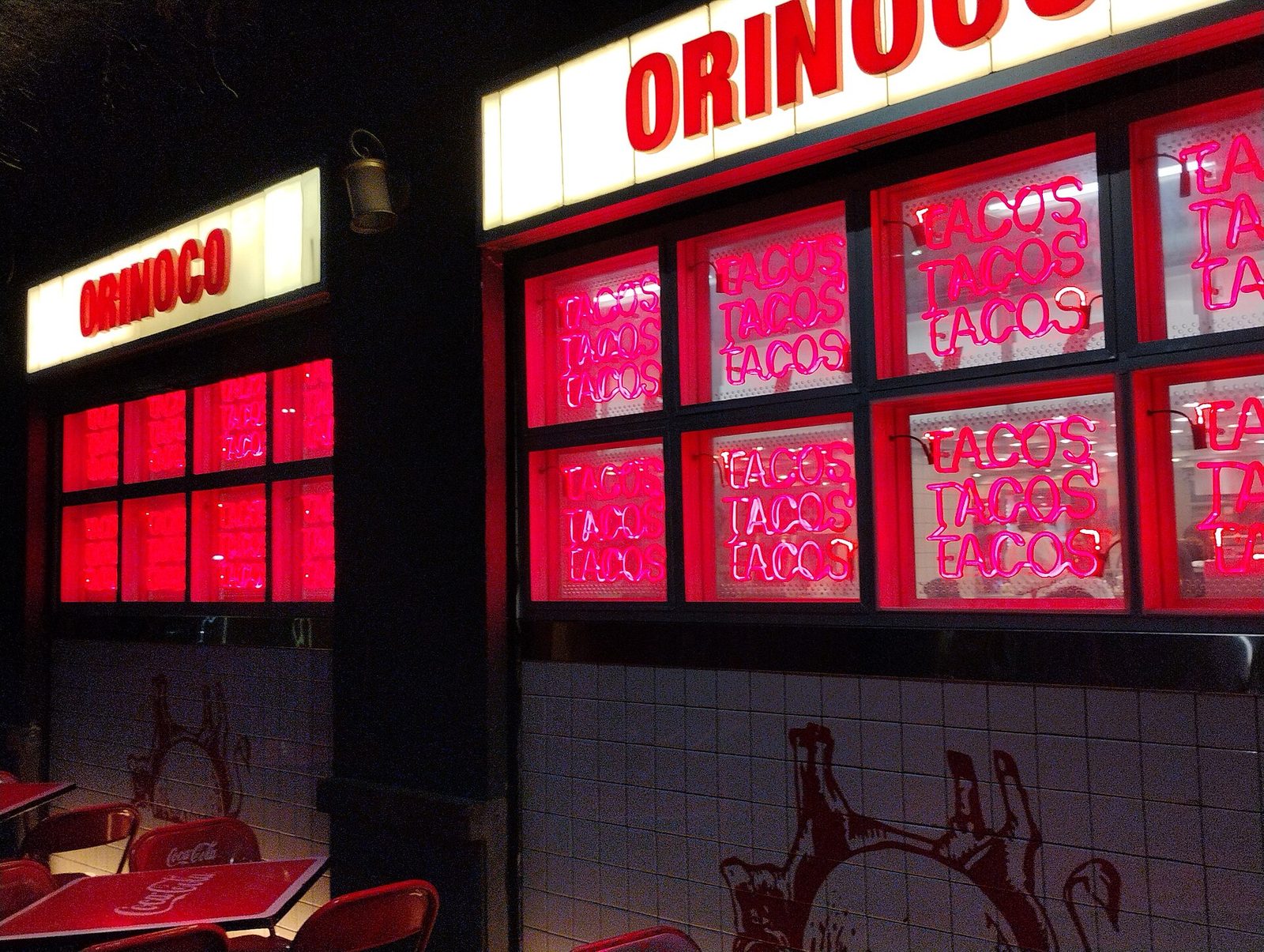 Taquería ORINOCO exterior at night, neon 'TACOS' signs in windows, Taquería Orinoco