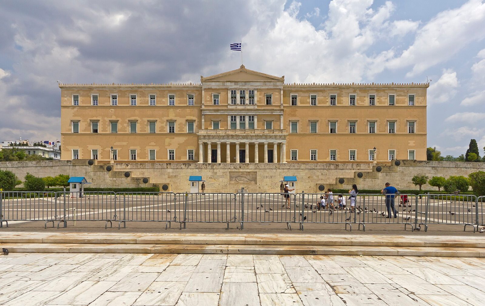 Front facade of a grand parliamentary building, empty forecourt and barriers, Athens