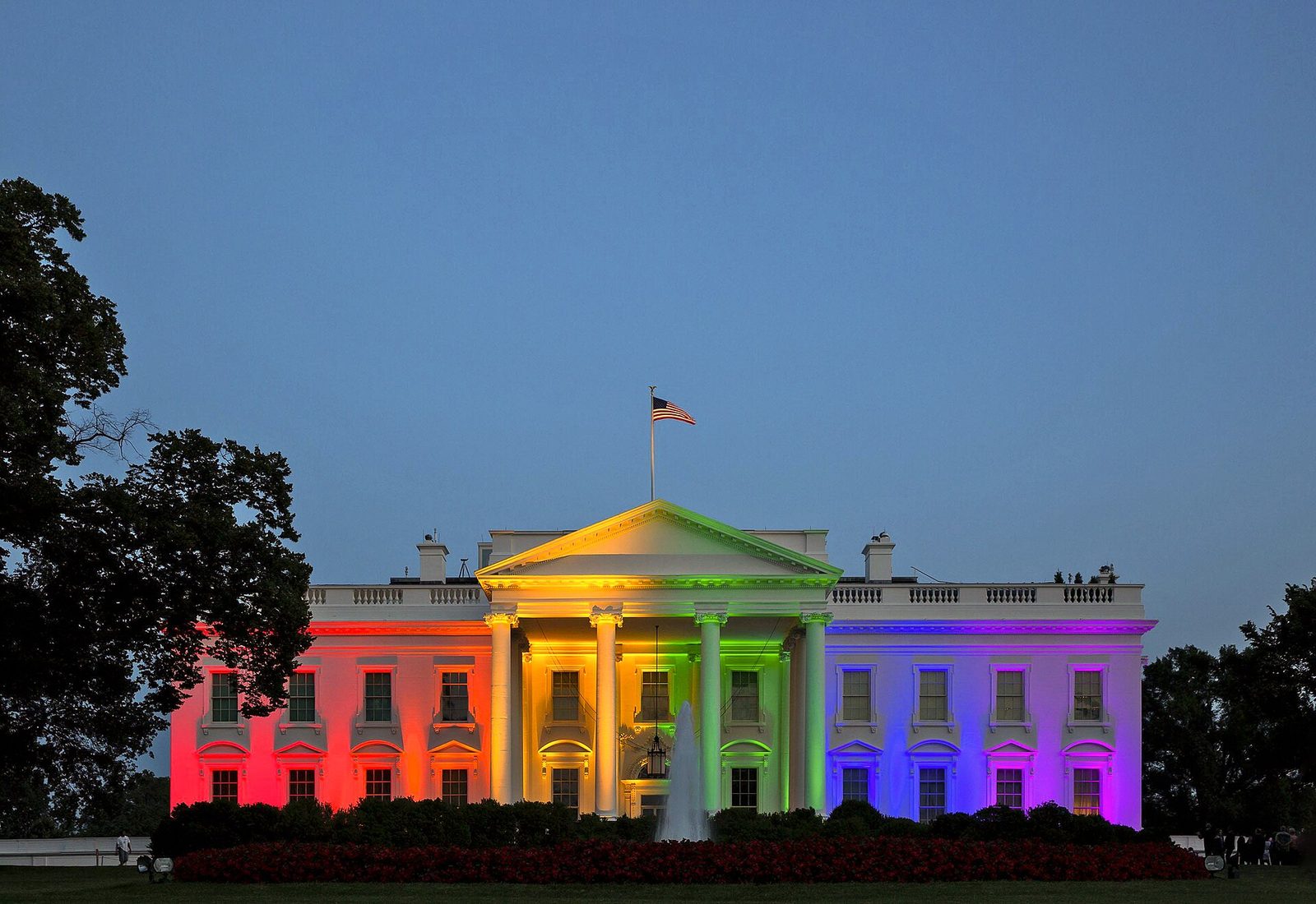 Neoclassical executive mansion lit in rainbow colours at dusk