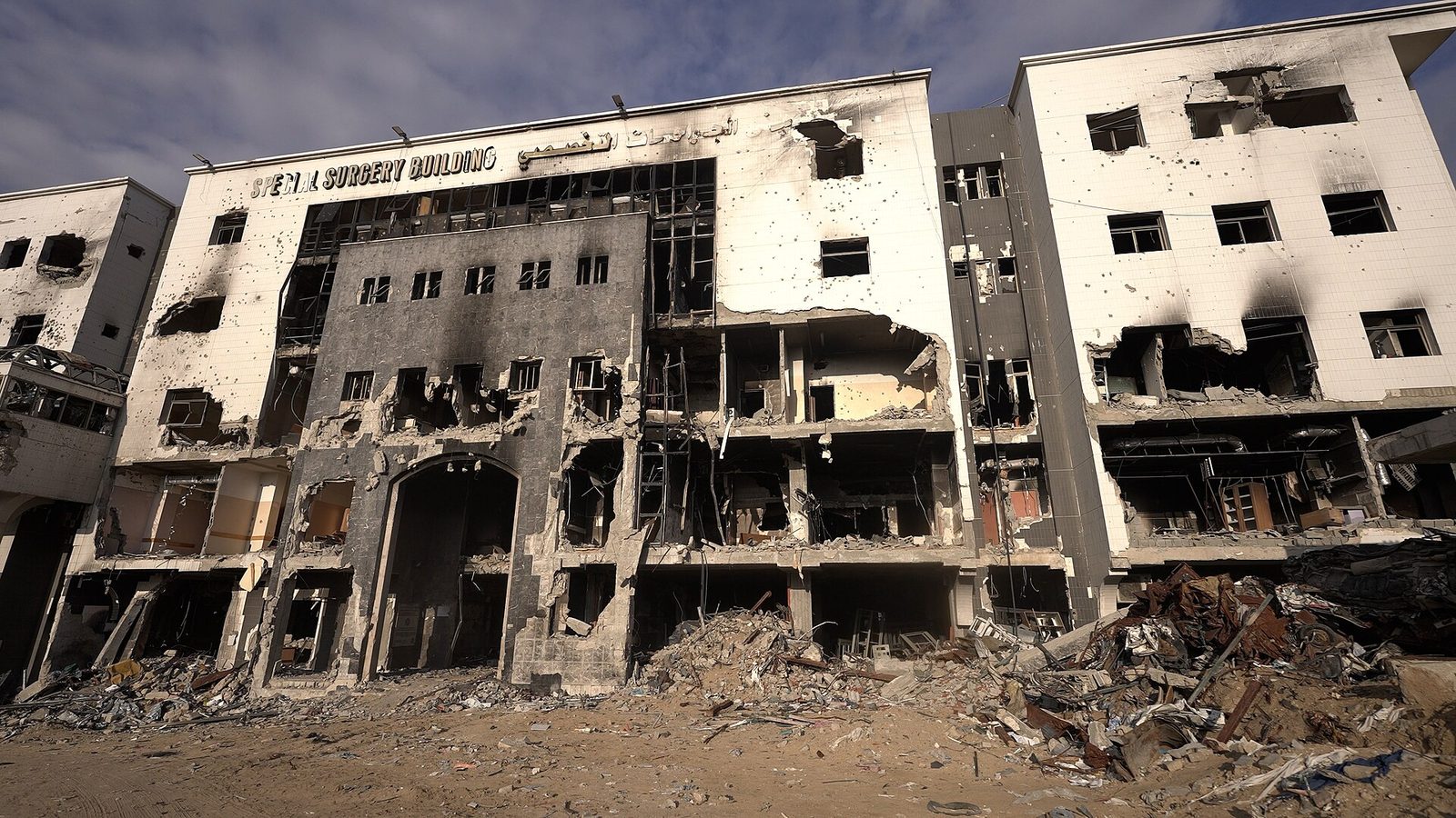 Damaged multi-storey hospital façade, blown-out windows, heaps of rubble, Al-Shifa Hospital