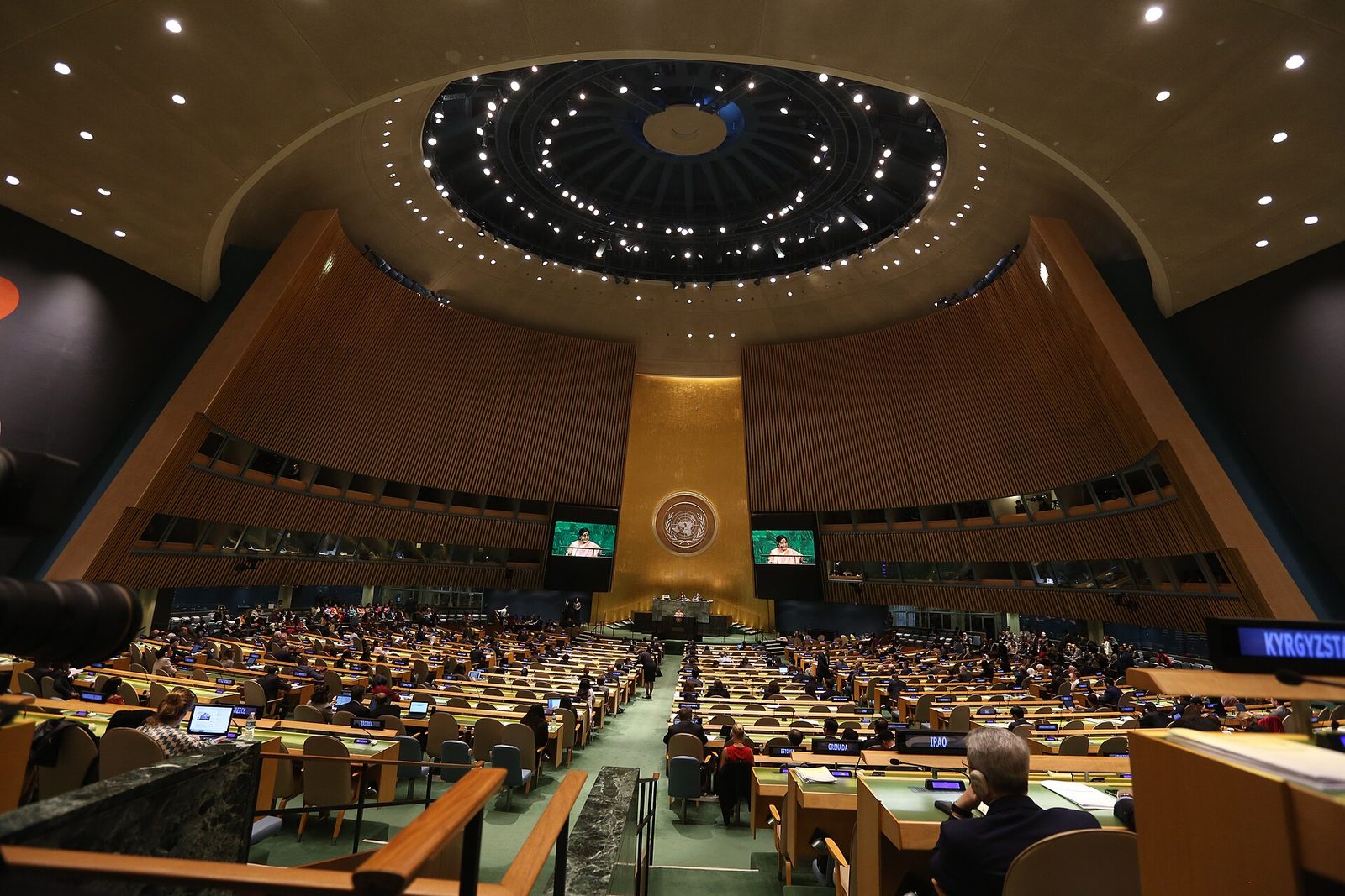 Wide shot of large assembly hall, many delegates at desks, United Nations General Assembly Hall