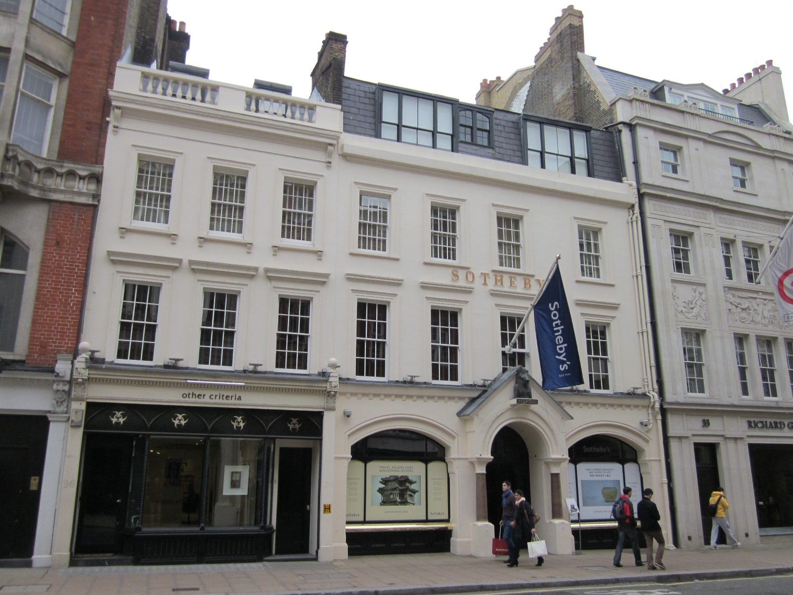 Wider view of Sotheby's New Bond Street façade with flag, passers-by, Sotheby's