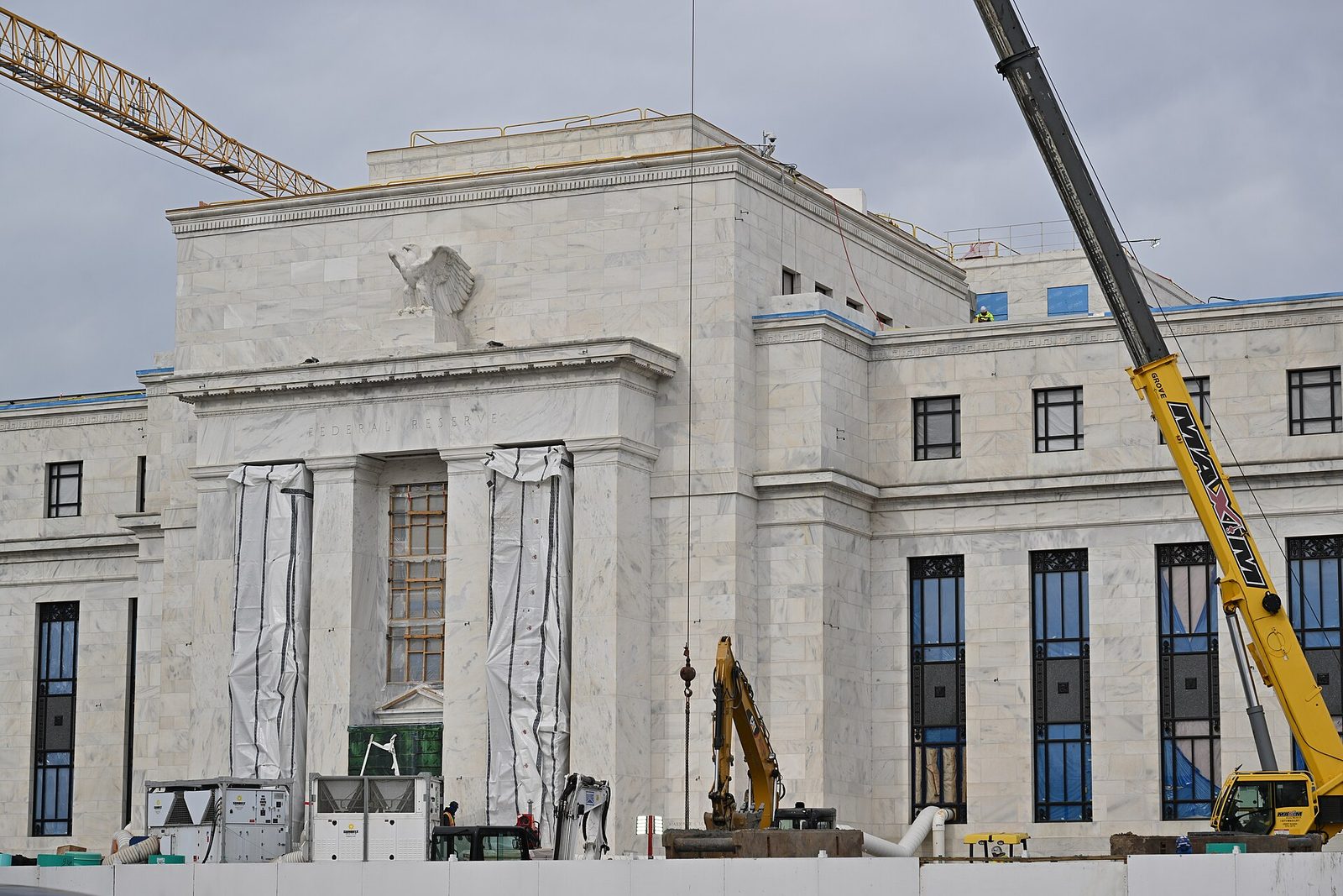 Large marble building under construction, crane arm at left, wrapped columns, Washington