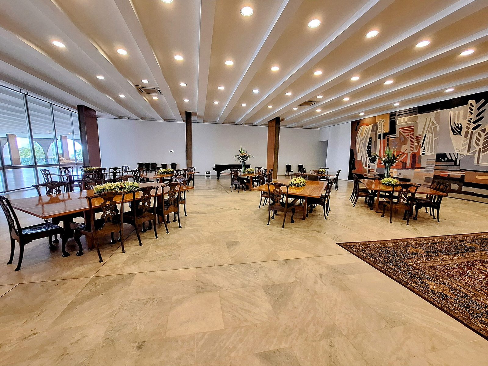 Large formal reception hall, wooden tables, ceiling lights, mural on wall, Brasília