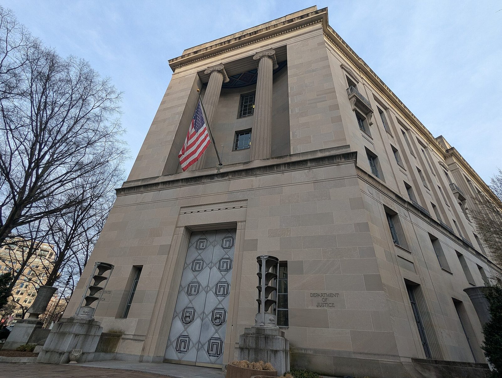 low-angle view of stone government building with flag and entrance