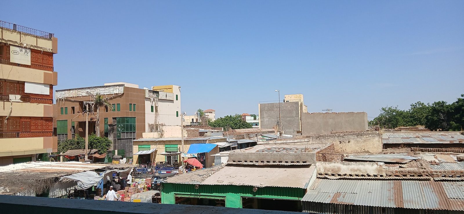 Wide view of market stalls, tin roofs and low-rise buildings, Nyala