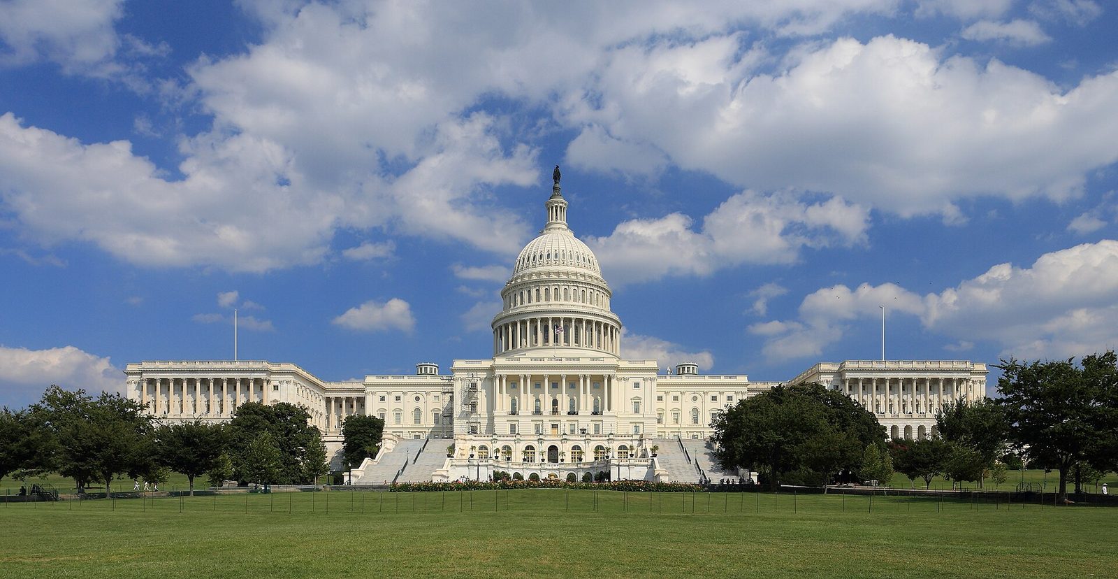 Large white domed government building, wide green lawn, blue sky