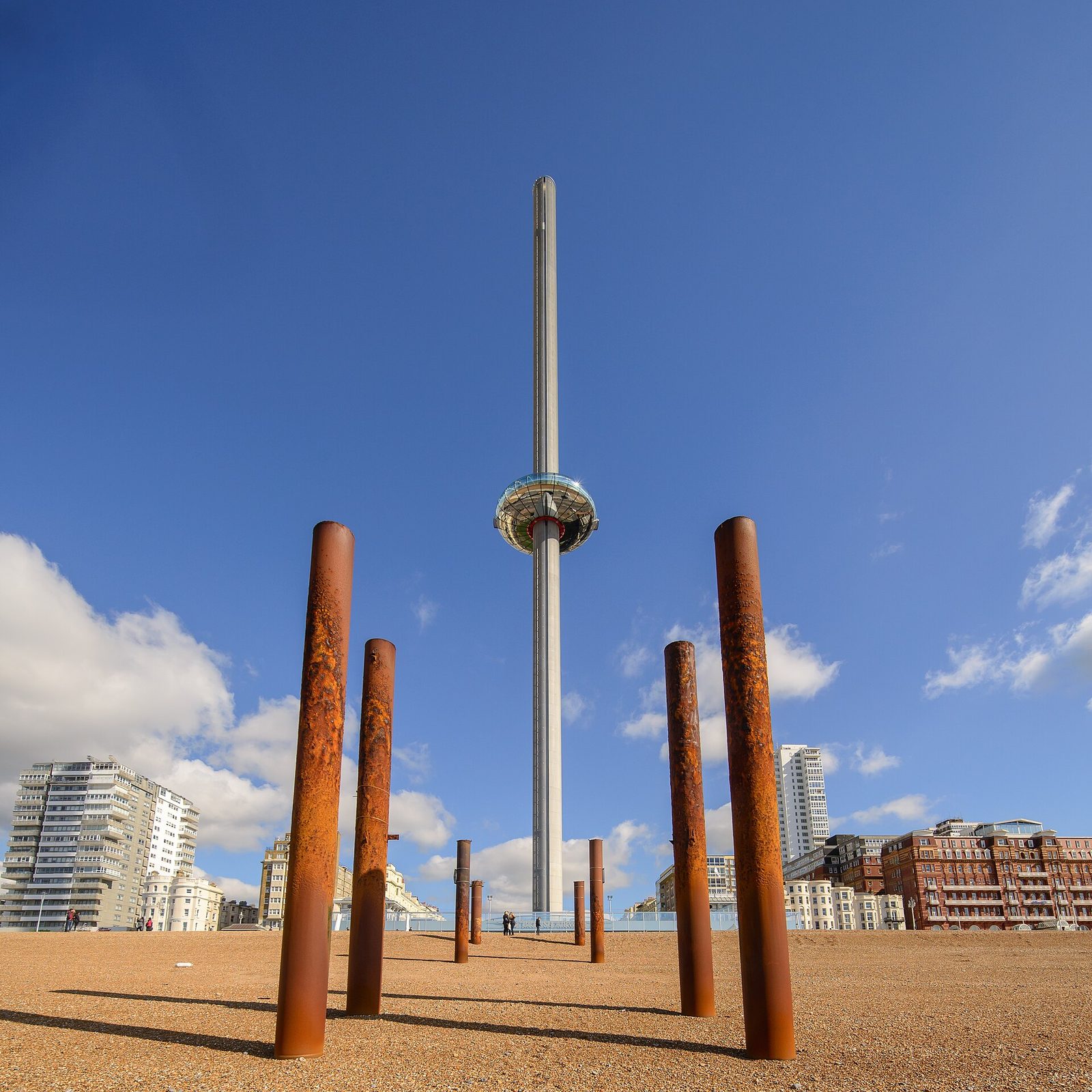 beach posts framing a tall observation tower, pier remains visible offshore, Brighton