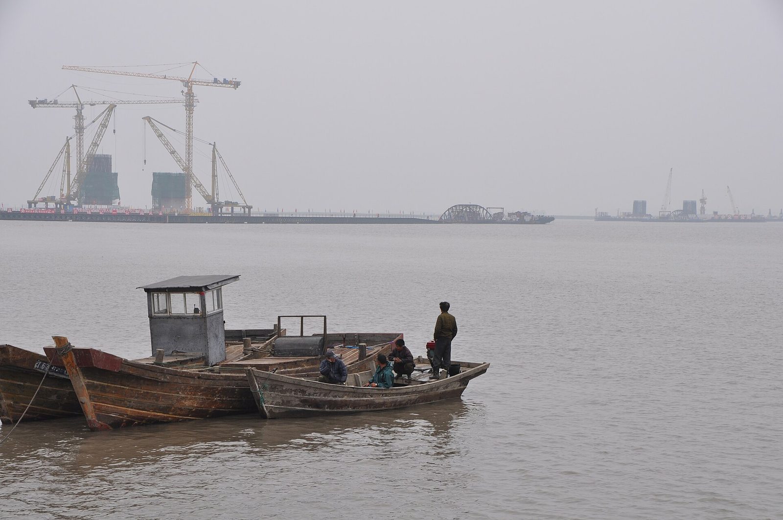 Boats on river, cranes and New Yalu Bridge construction visible