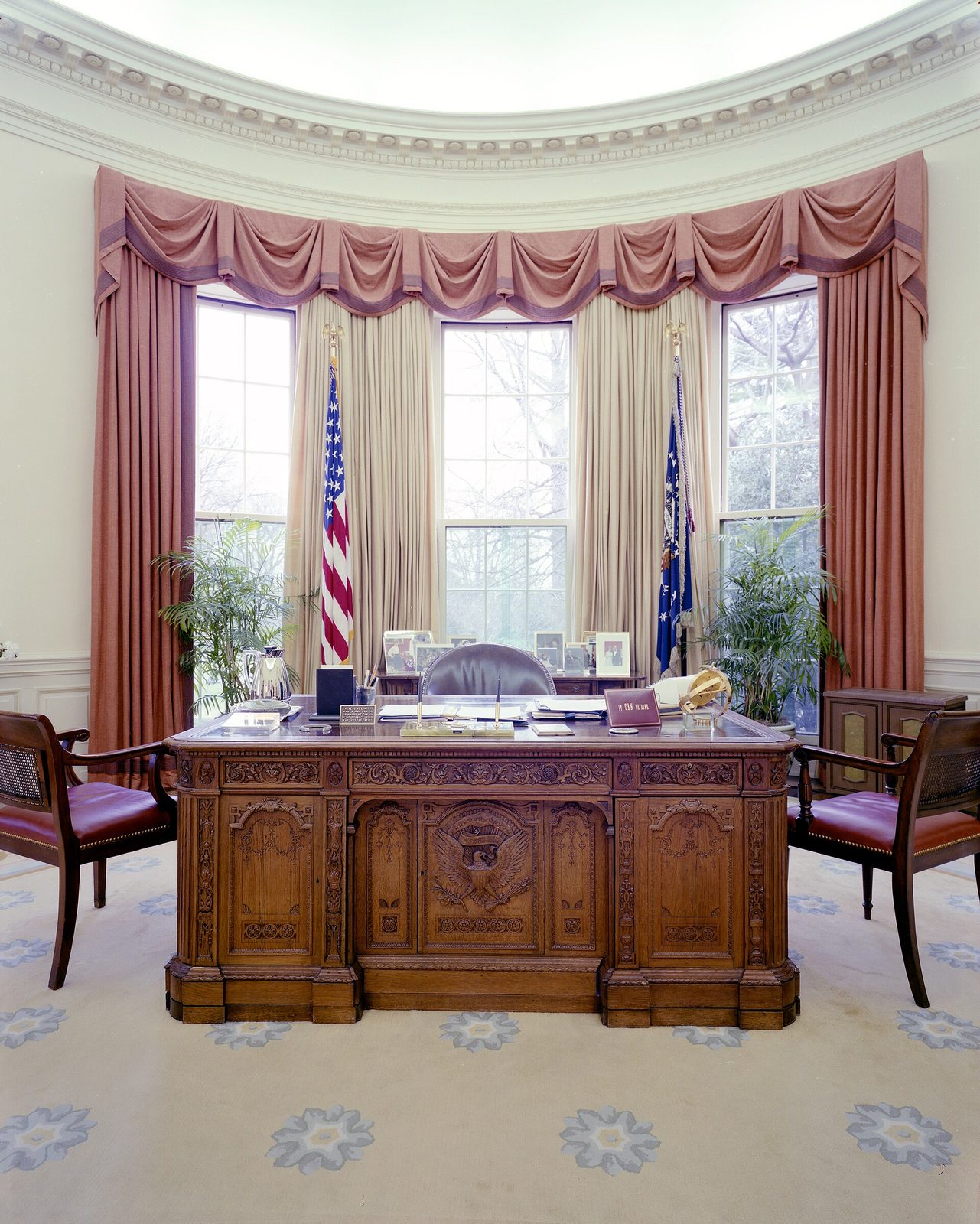 Formal office interior with carved desk and tall draped windows