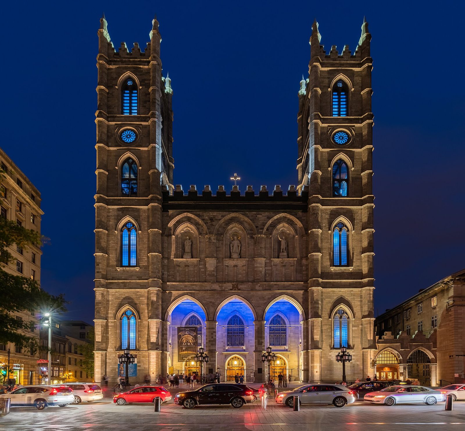 Stone church façade at dusk, twin towers and lit entrances, Montreal