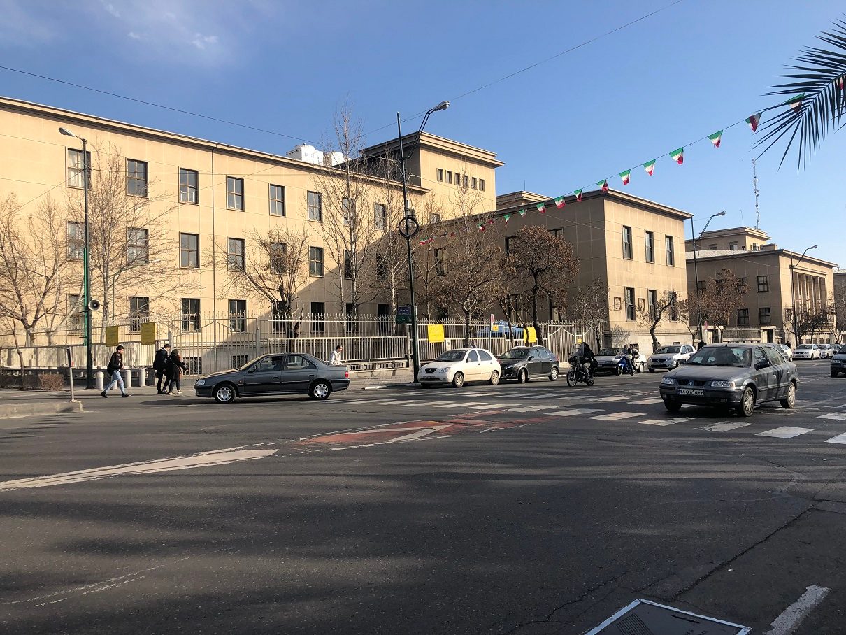 wide street view of multi storey courthouse behind a fence