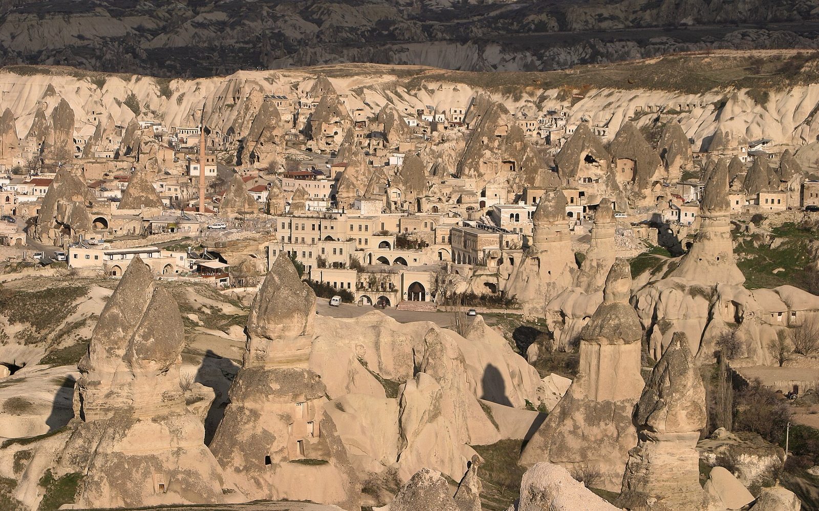 Valley of fairy chimneys with town buildings behind, layered rock formations