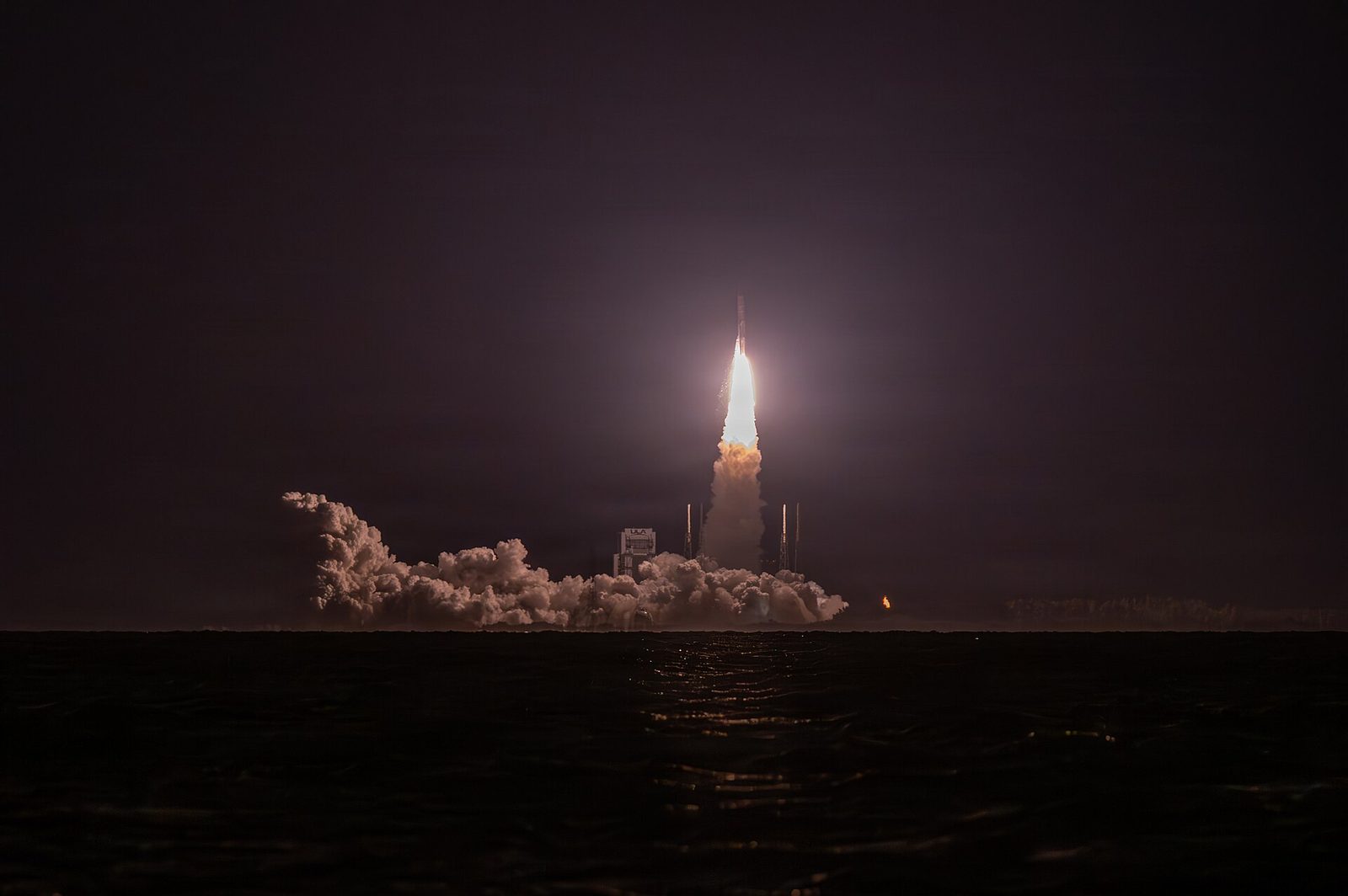 rocket liftoff from pad, plume and smoke, sea foreground