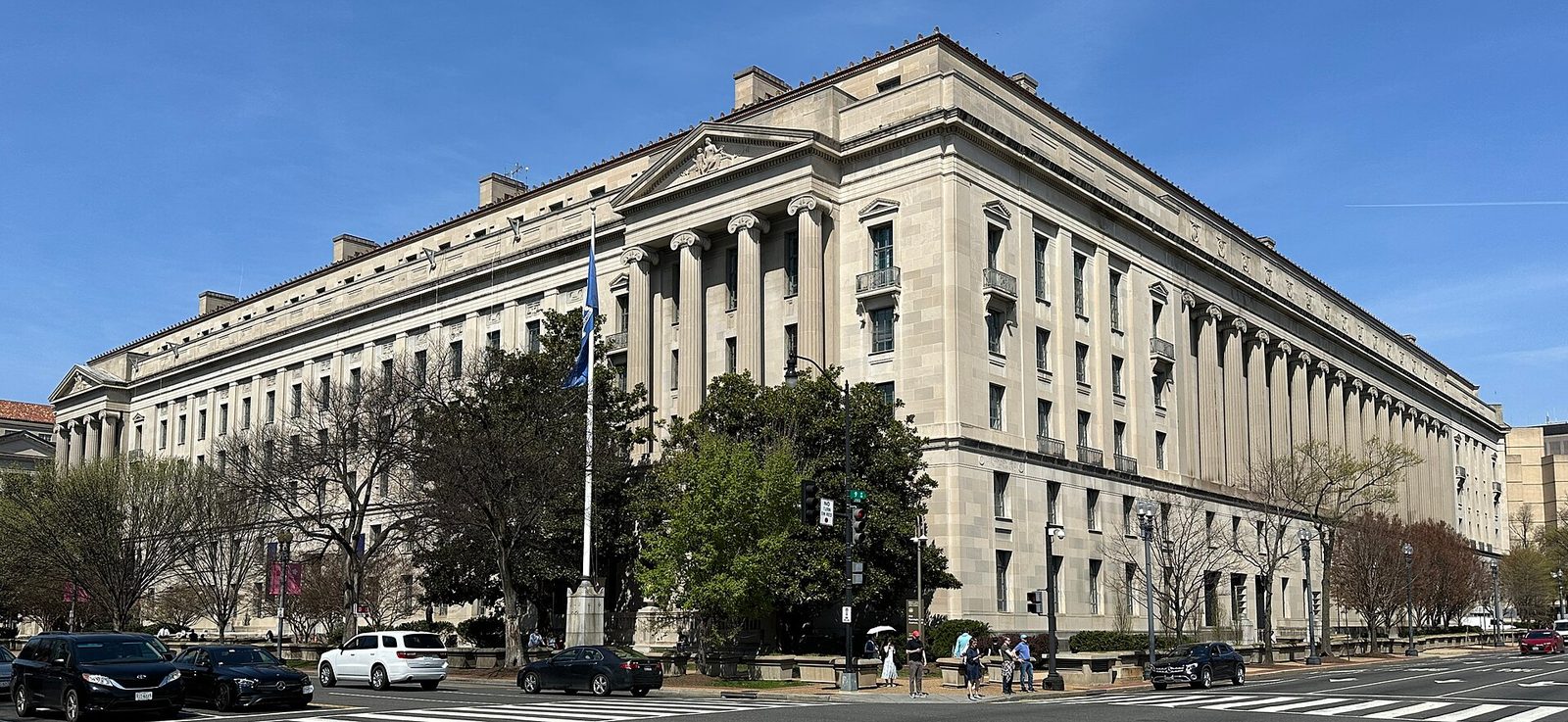 Neoclassical government building, crosswalk and pedestrians under a blue sky