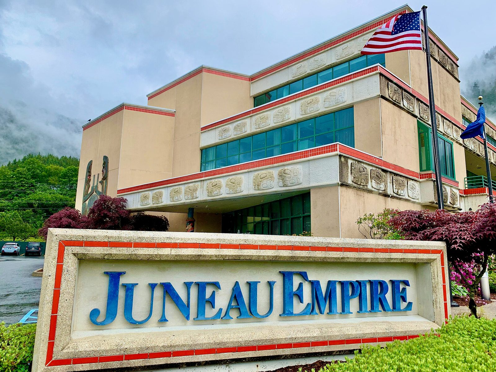 Office building with sign reading 'JUNEAU EMPIRE', flag on a pole