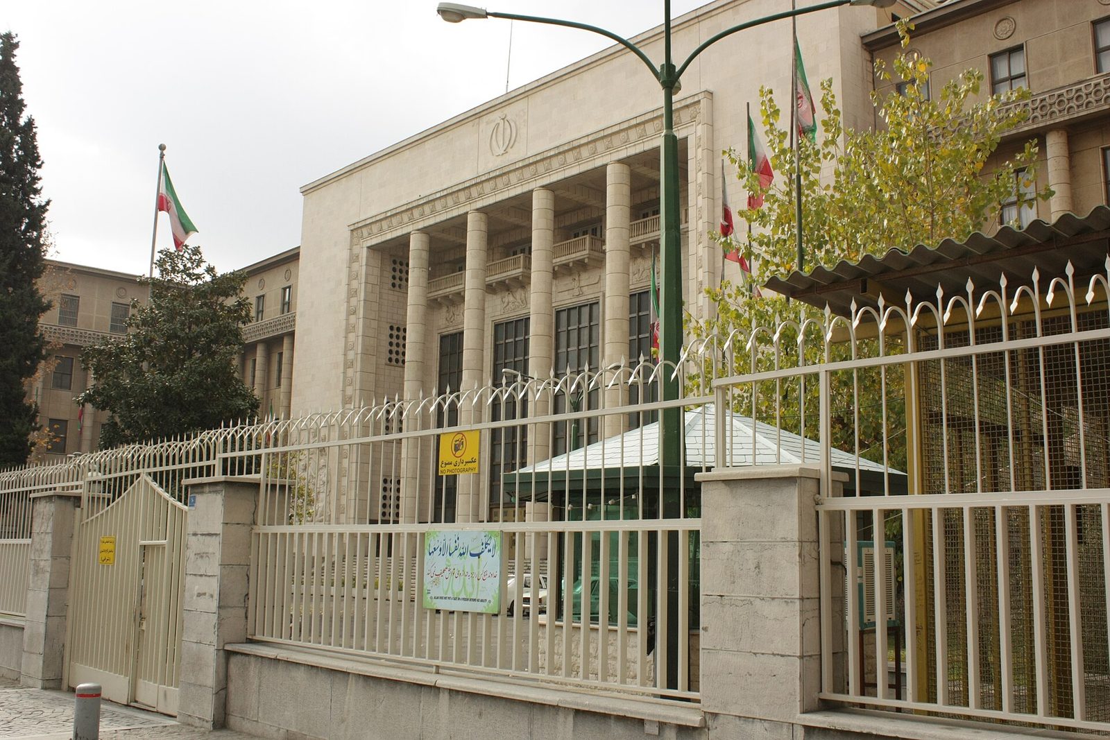 large stone courthouse facade with columns, fence and flags