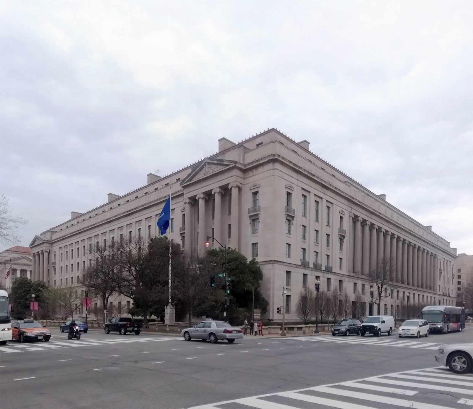 Neoclassical government building at a busy intersection, cars and crosswalk