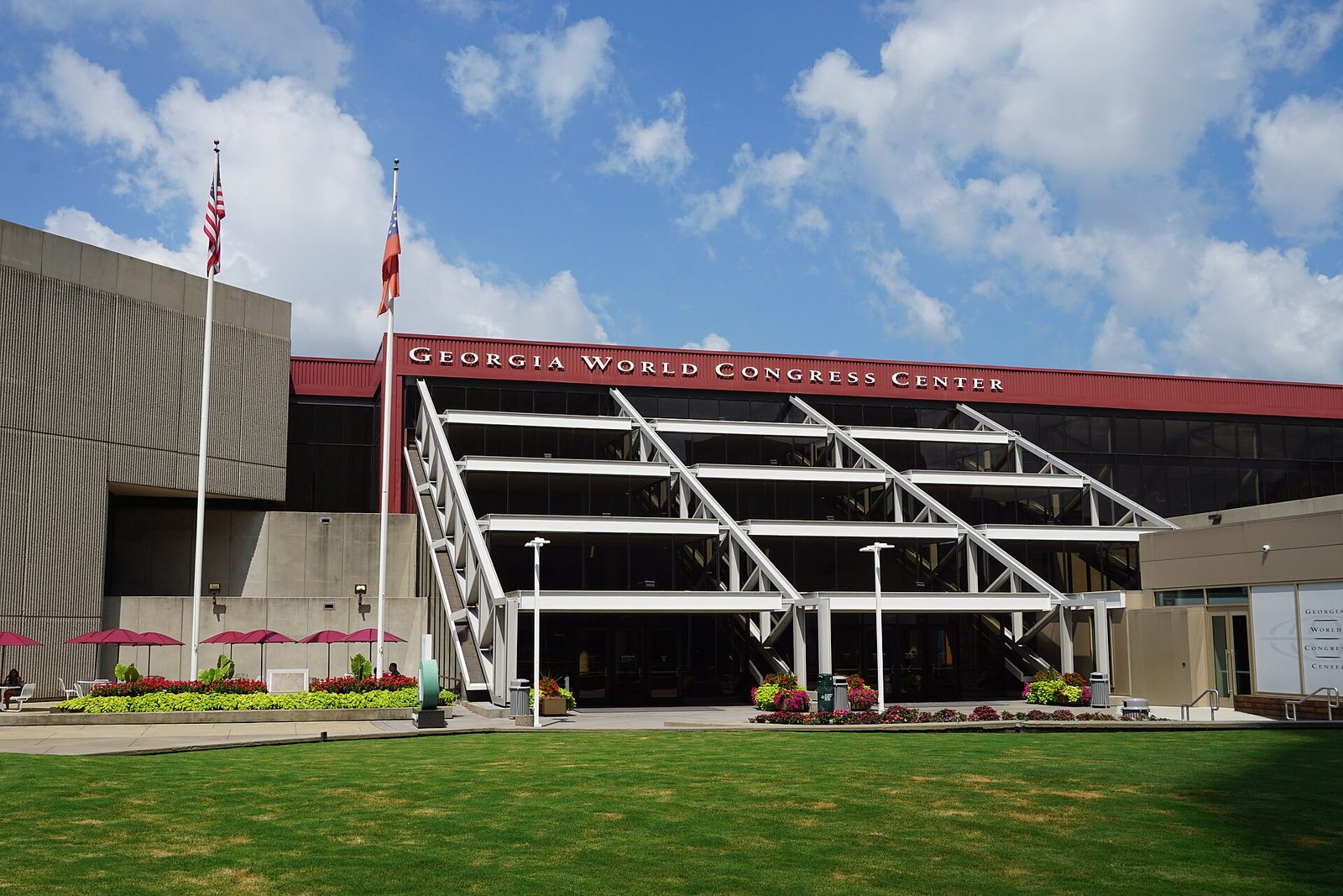 exterior entrance of a large glass-faced convention centre, flags and lawn, Atlanta