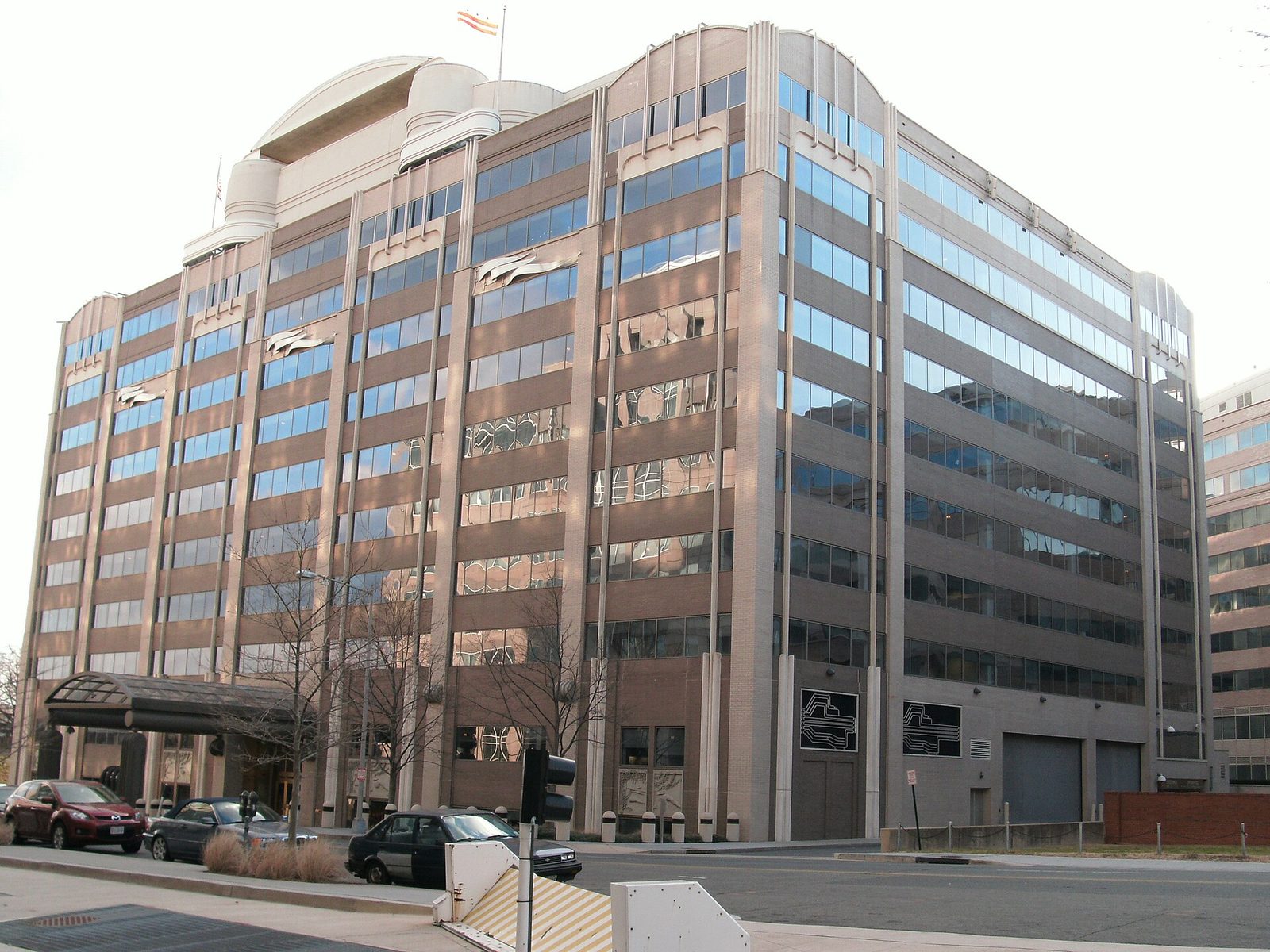 Large multi-storey office building with reflective windows, vehicles on the street, Washington