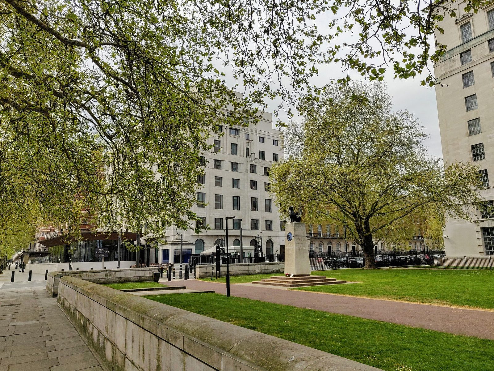 New Scotland Yard building with trees and a small memorial in front, New Scotland Yard