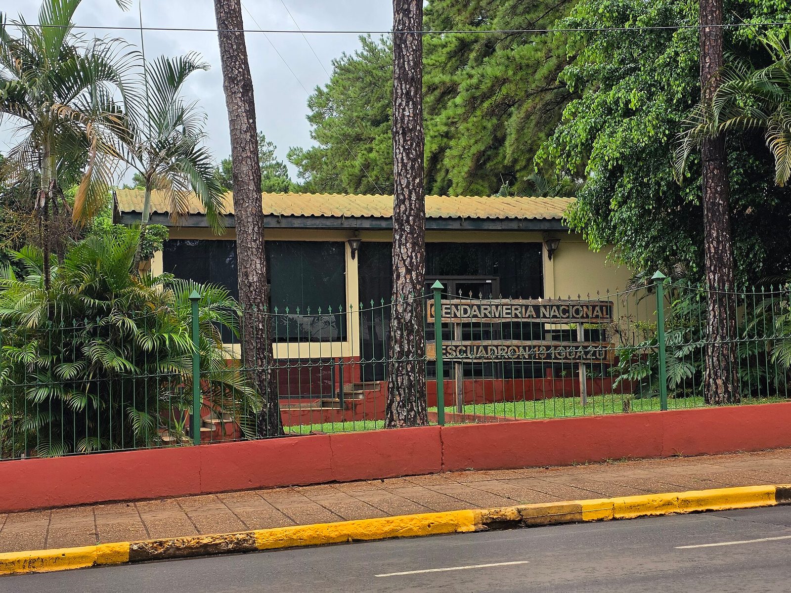 Small fenced building, sign reading 'GENDARMERIA NACIONAL', trees around