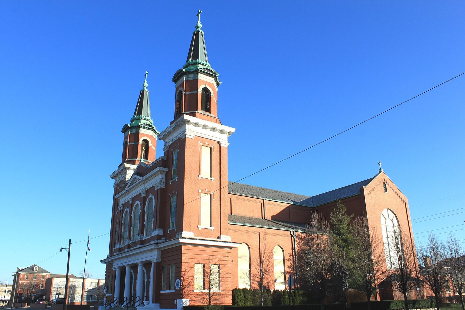 Large brick Catholic church with twin spires under a clear blue sky, Wyandotte