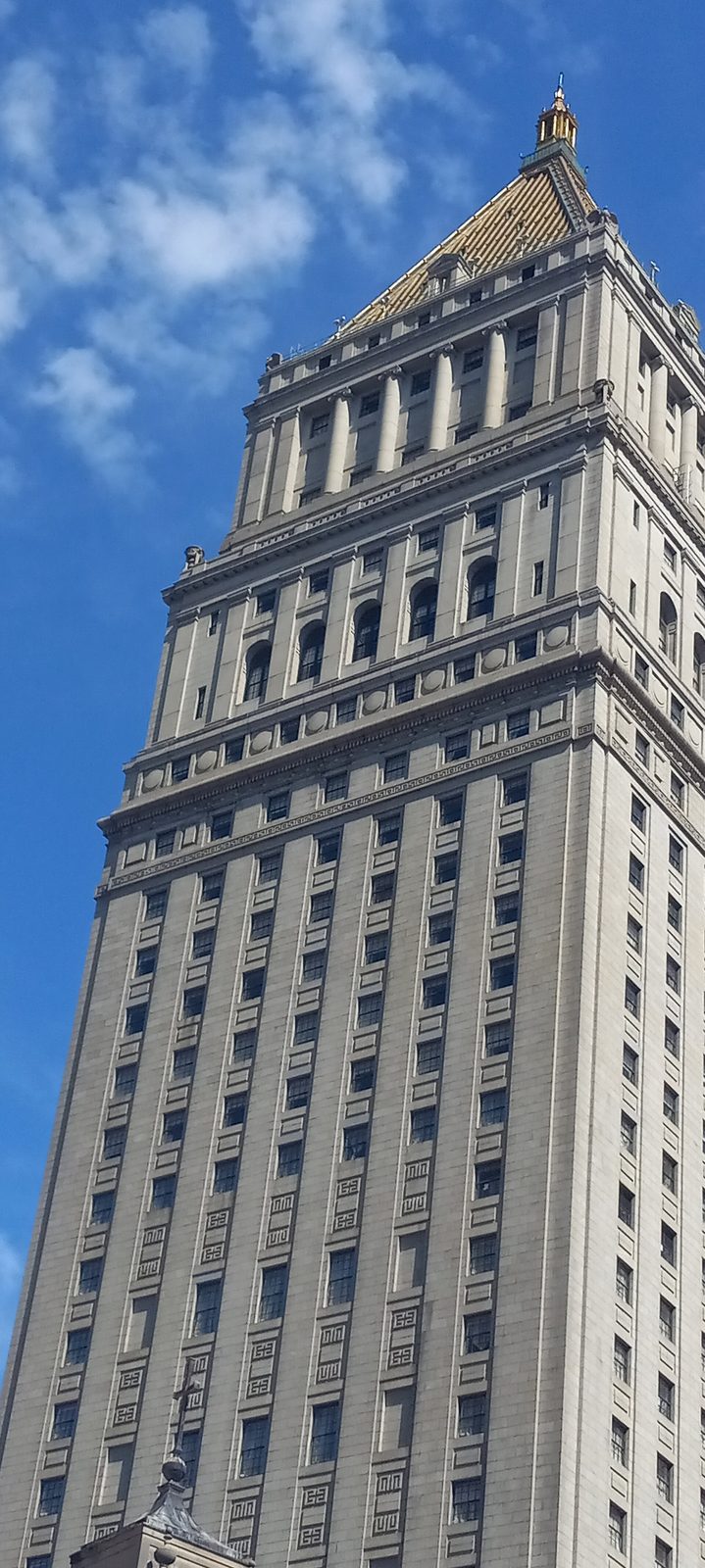 tall limestone civic building tower with a pyramidal roof, clear blue sky, Manhattan