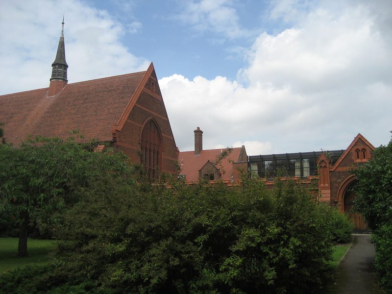 Red-brick chapel and college buildings, lawns and cloudy sky, Girton College