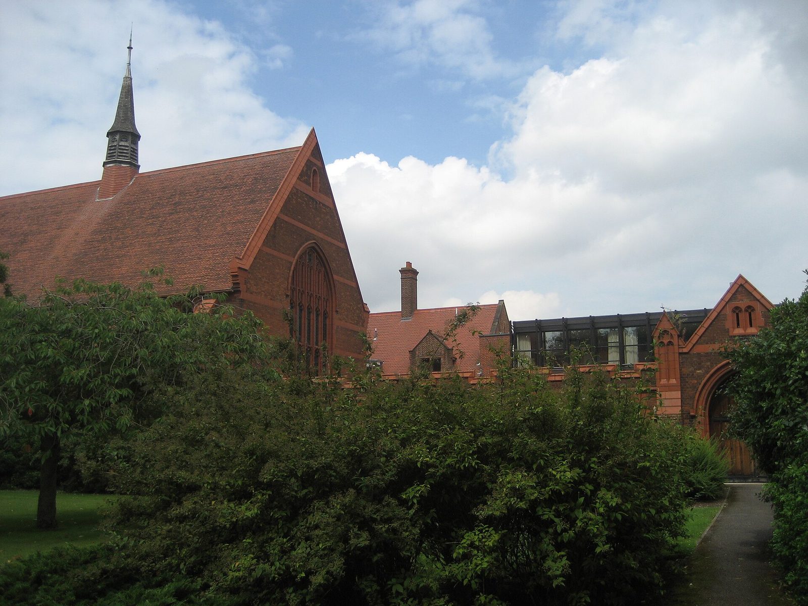 Red-brick chapel and college buildings, lawns and cloudy sky, Girton College