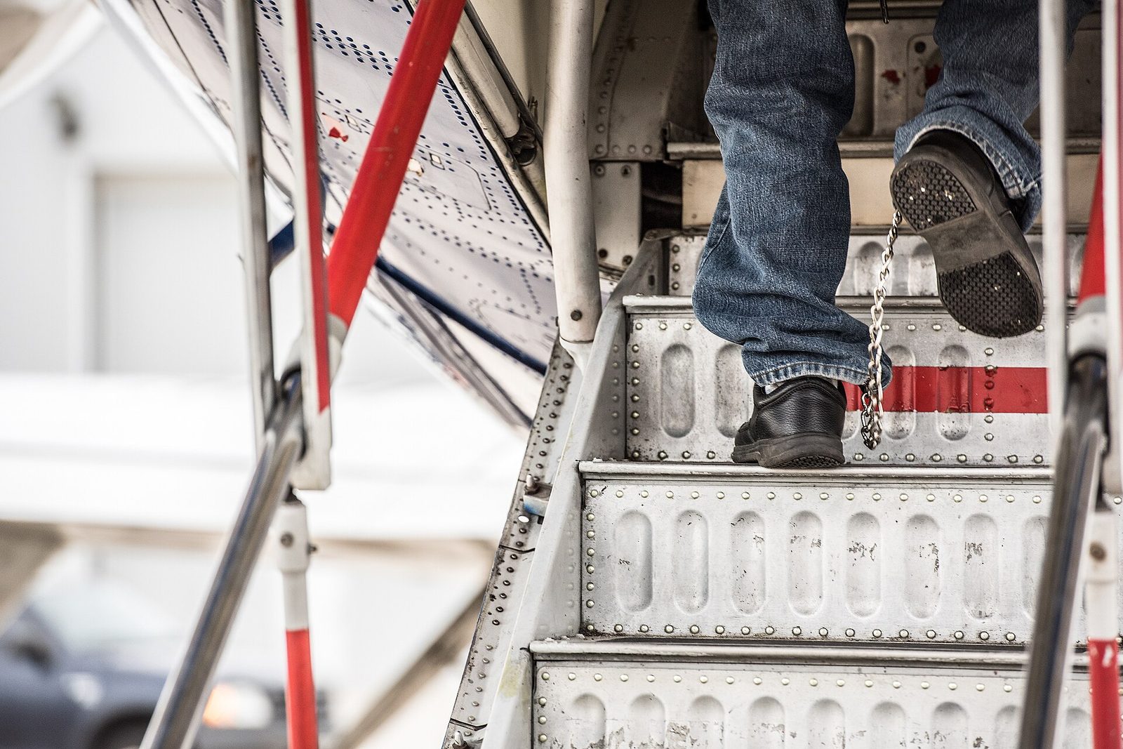 person's feet ascending aircraft stairs, ankle chain clearly visible